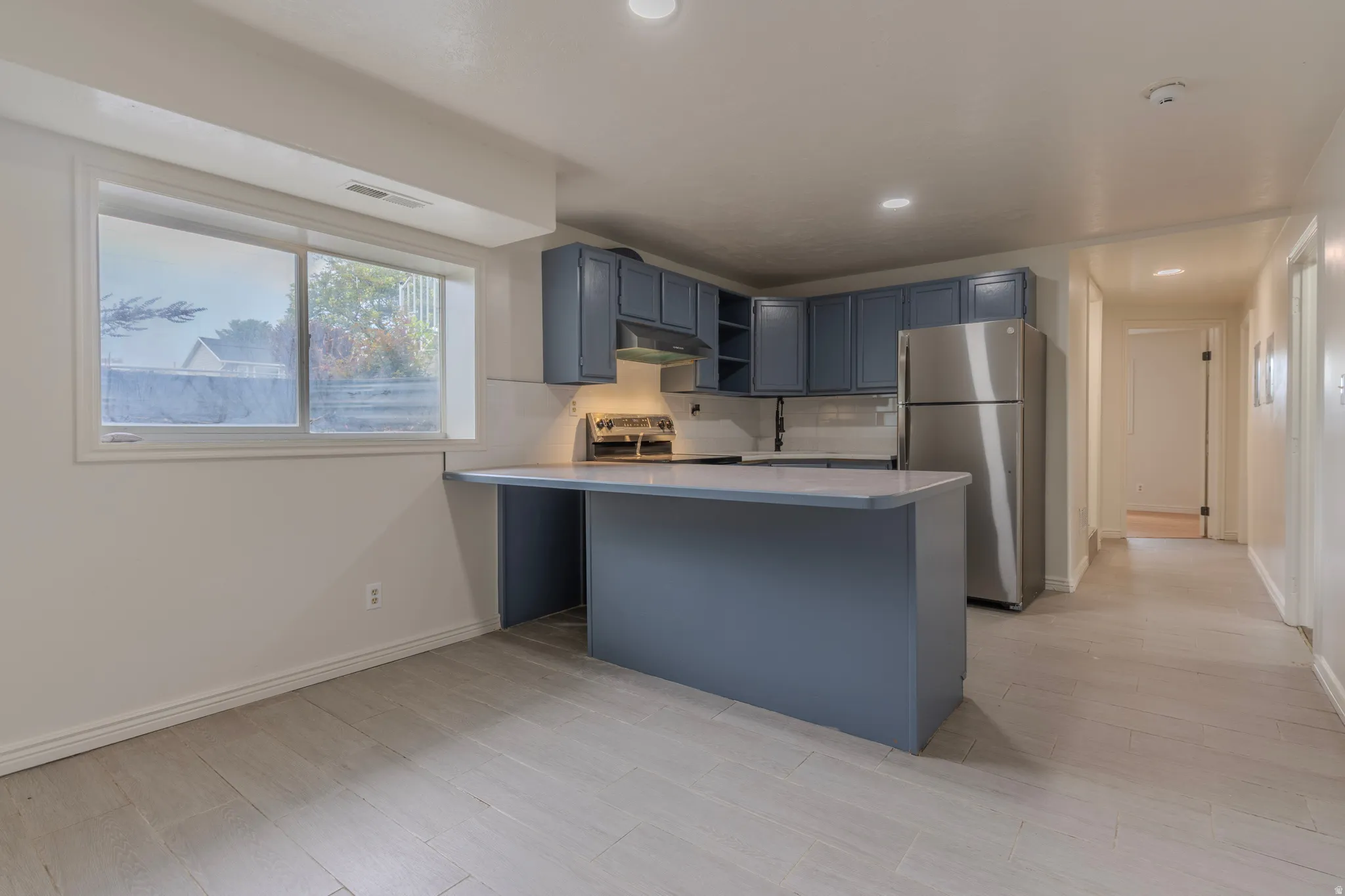 Kitchen featuring blue cabinetry, a stainless steel refrigerator, light-toned countertops, and tile flooring