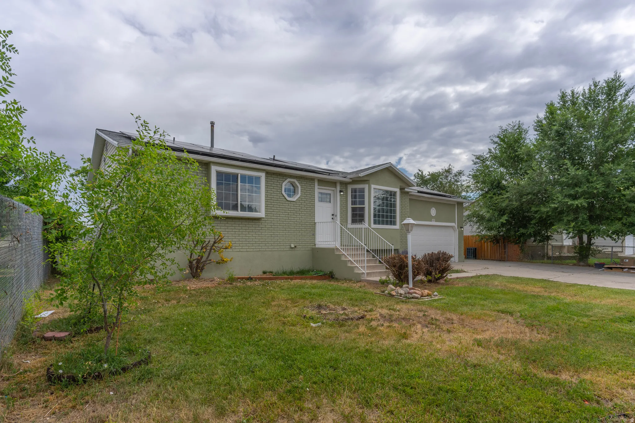 Ranch-style residence featuring a light green exterior, white trim, and an attached garage