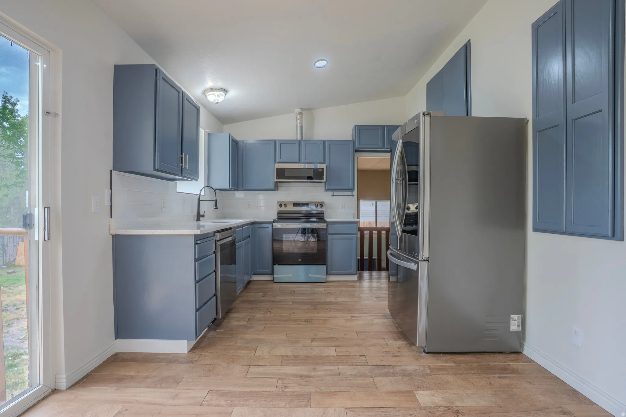 Kitchen featuring blue cabinetry, light wood-finish flooring, and white countertops