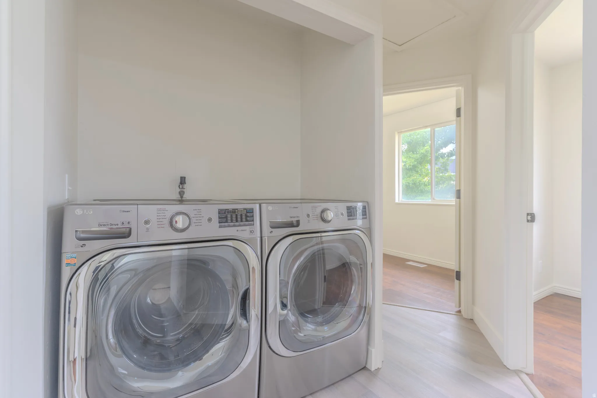 Dedicated laundry area featuring light wood-finish flooring