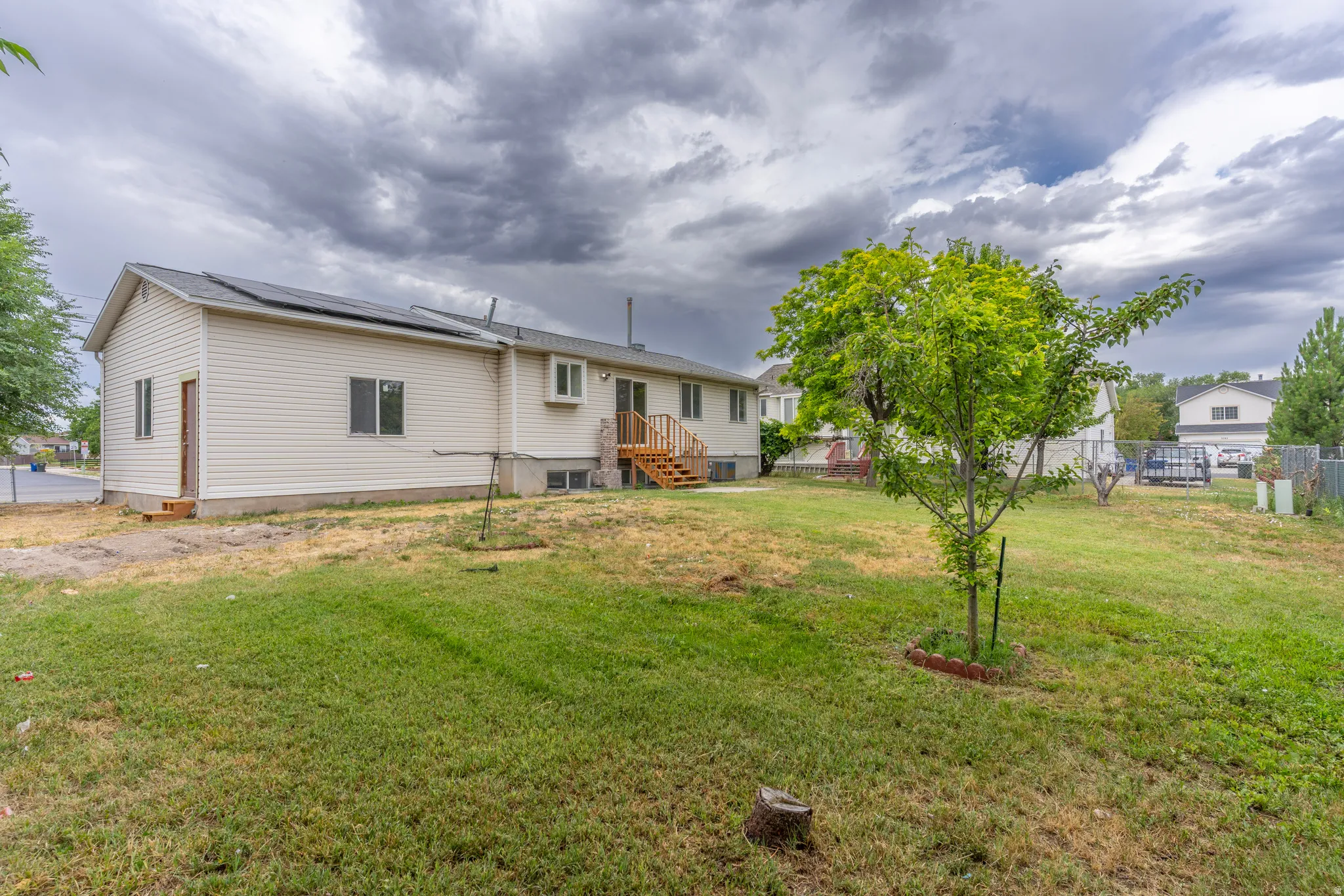 Spacious backyard featuring a large green lawn and mature landscaping