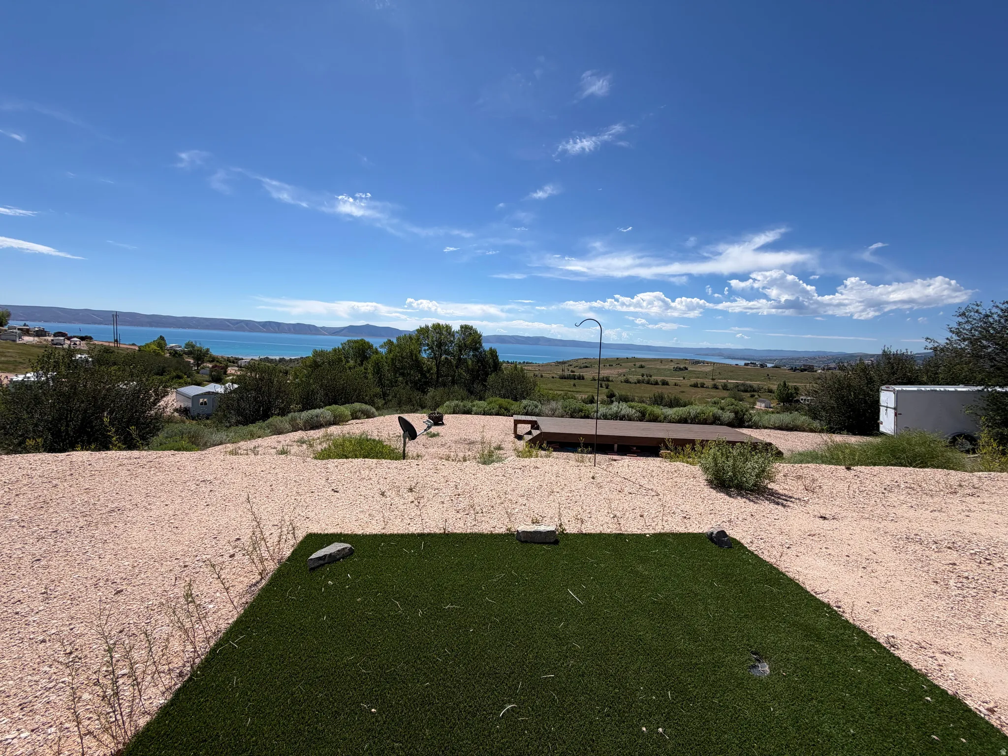 Expansive outdoor space featuring a large artificial turf area and a broad deck with a lake backdrop