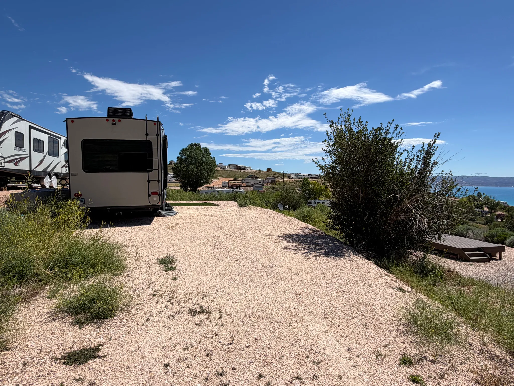 Gravel surface lot featuring a multi-level wooden deck and water scenery