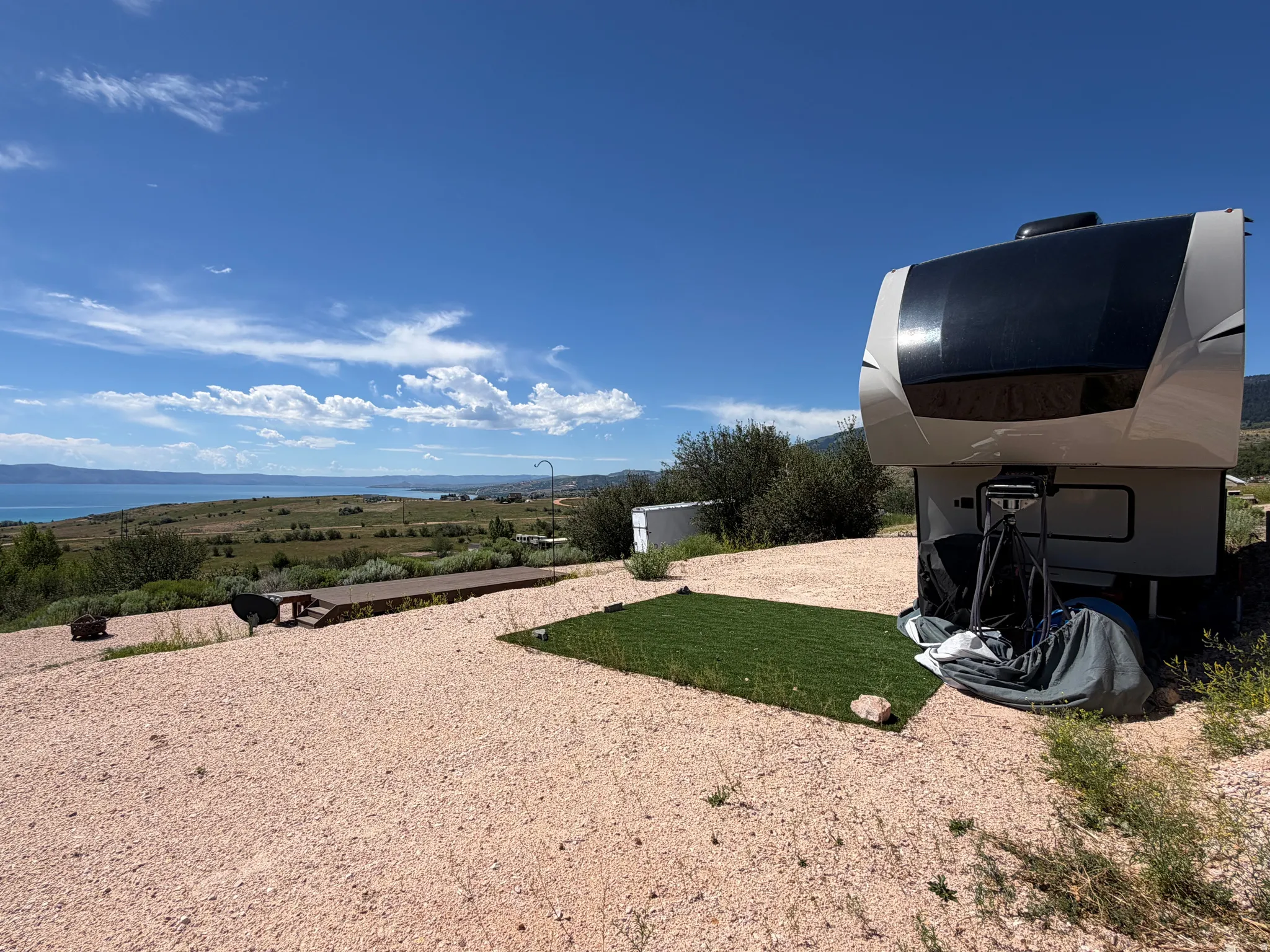 Expansive gravel lot featuring a level, artificial turf pad, and a large wooden deck
