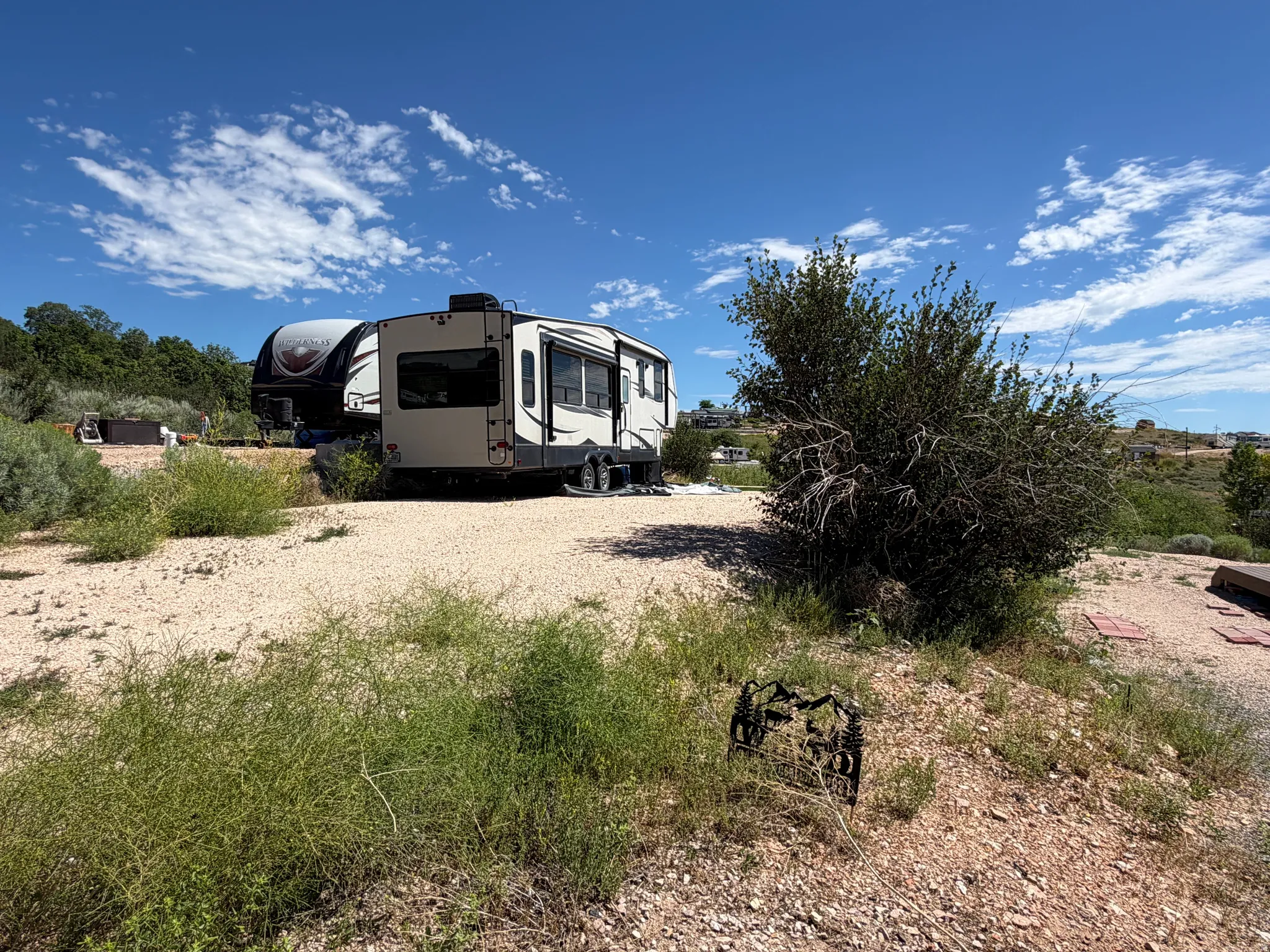Gravel lot featuring a large RV and natural desert landscaping