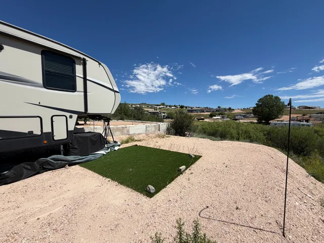 Gravel lot featuring a square of artificial turf and distant structures