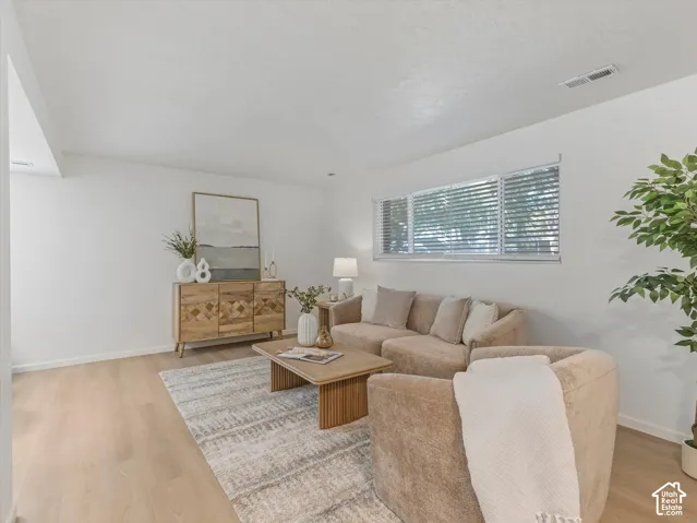 Wood-finish flooring throughout, white painted walls, and a large window with horizontal blinds