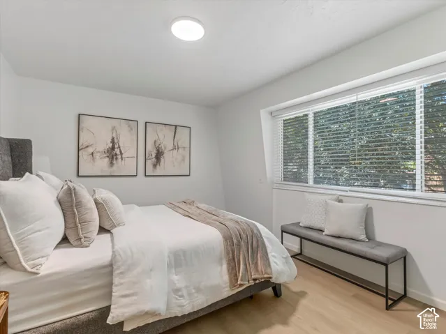 Expansive window with horizontal blinds, wood-finish flooring, and recessed ceiling lighting