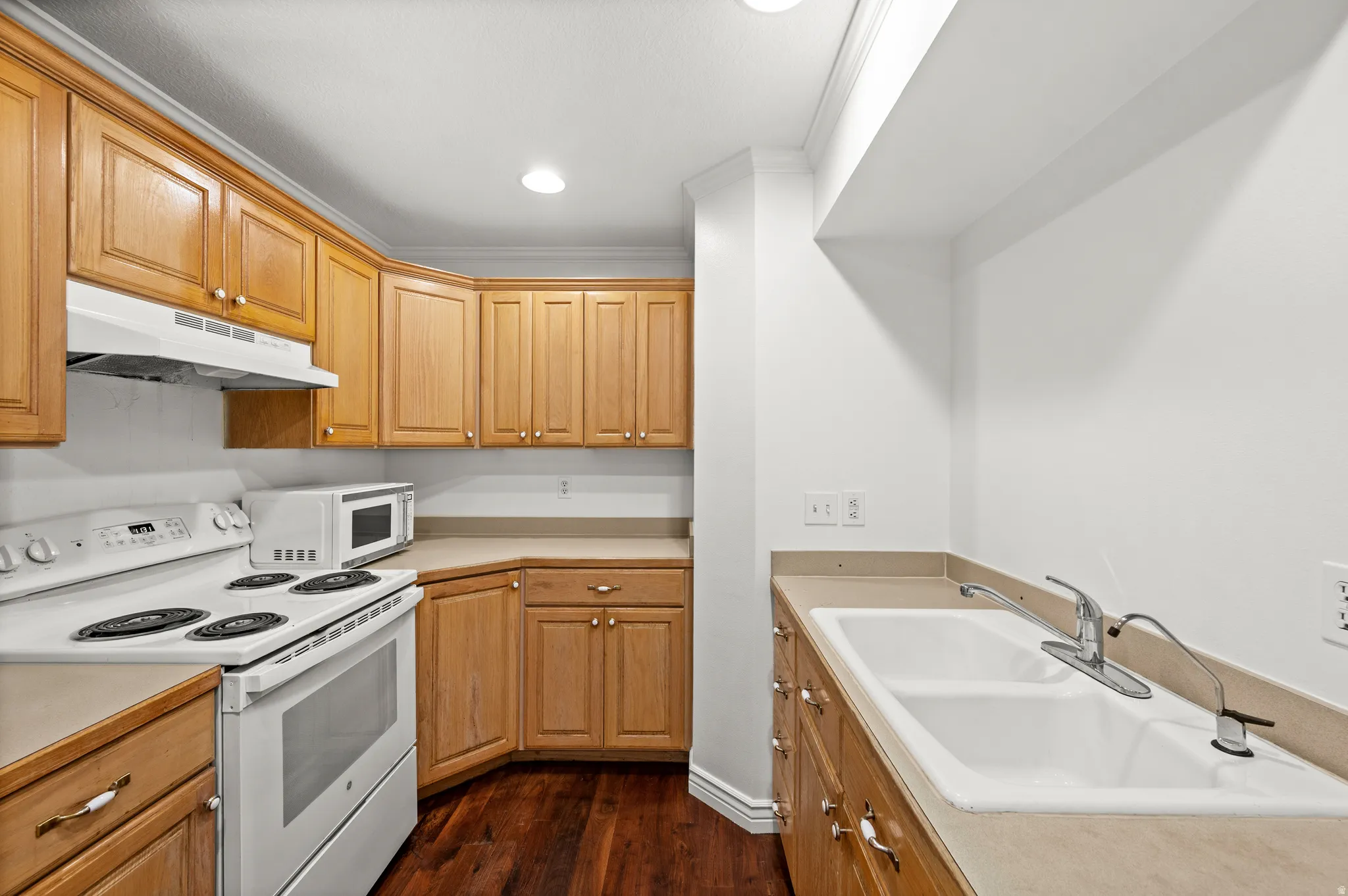 Hardwood-finish flooring, light wood cabinetry, a double basin sink, and a white electric range