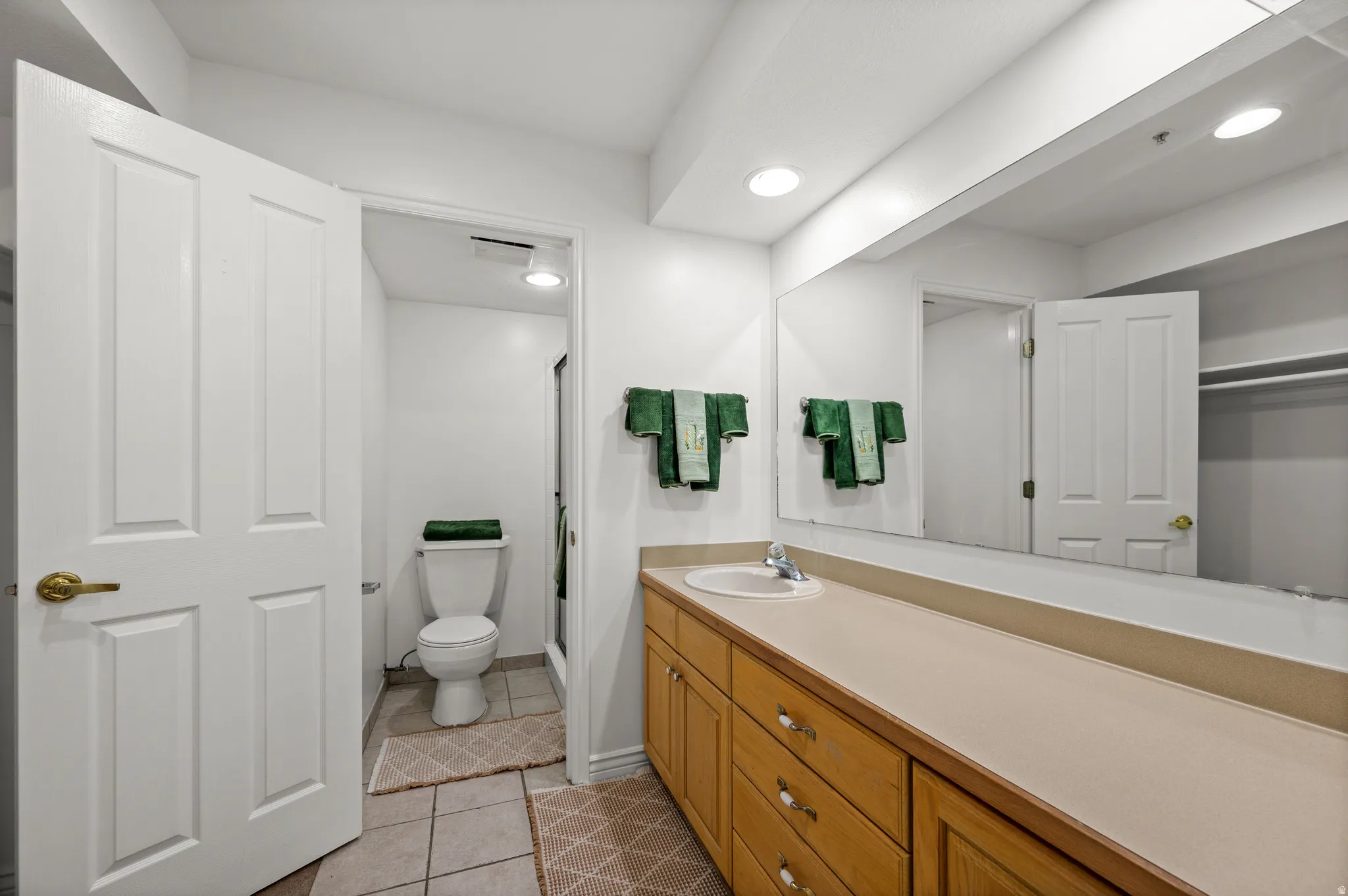 Bathroom with a single vanity, wood cabinetry, a large wall-mounted mirror, and tile flooring