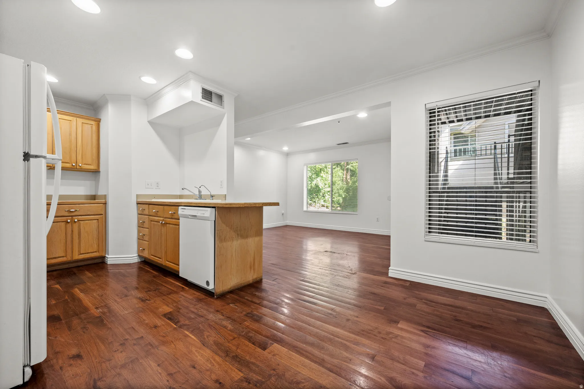Kitchen featuring wood-finish flooring, wood cabinetry, built-in dishwasher, and recessed lighting