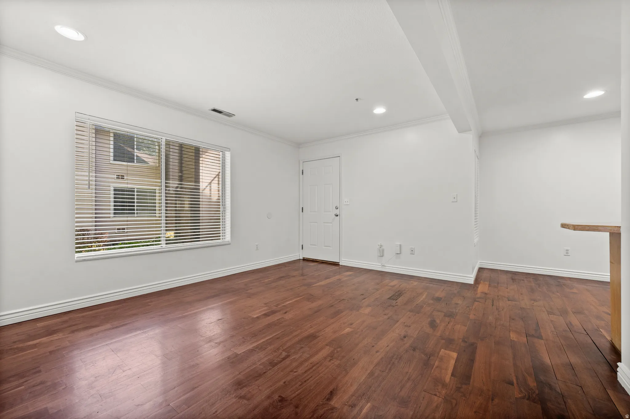 Rich wood-finish flooring, recessed lighting, and a white interior door