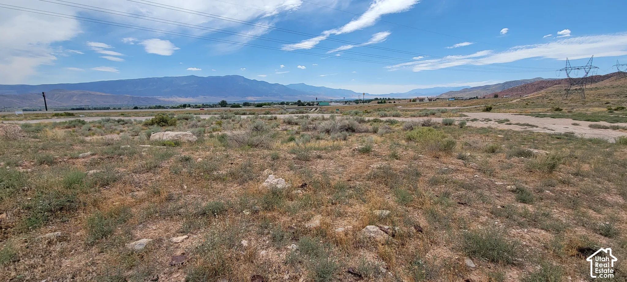 Expansive undeveloped land featuring natural desert vegetation, rolling terrain, and distant mountain ranges