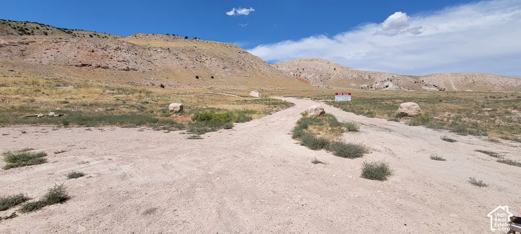 Expansive undeveloped land featuring a dirt road, sparse vegetation, and distant hills