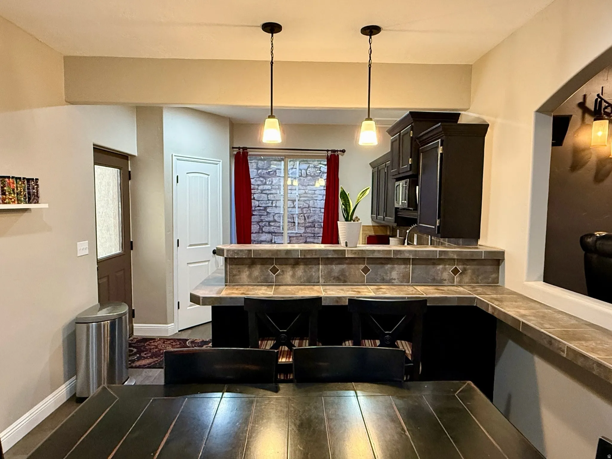 Kitchen featuring dark wood cabinetry, tile countertops with a decorative backsplash, and a built-in microwave