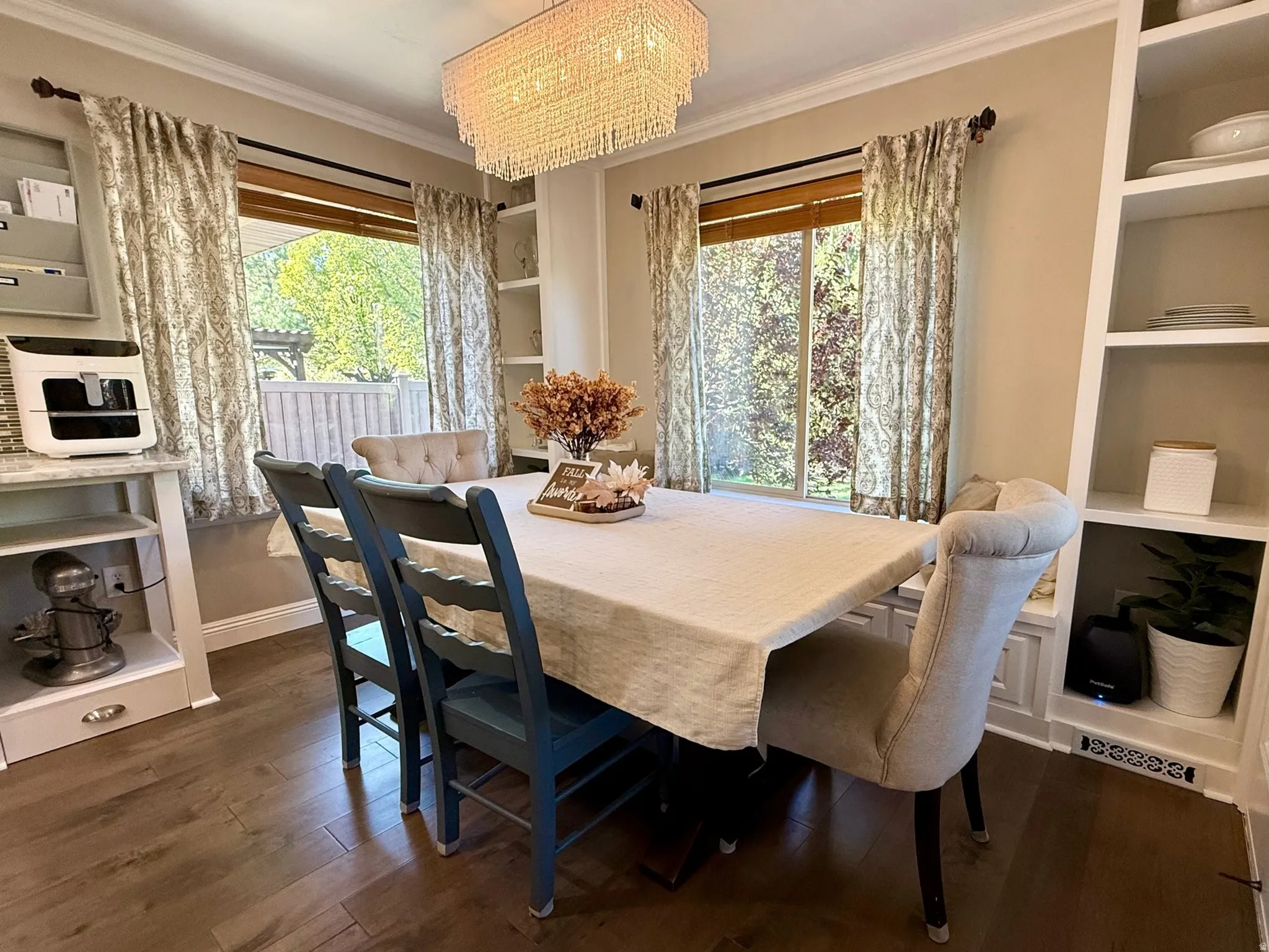 Dining area featuring wood-finish flooring, two large windows, and a crystal chandelier