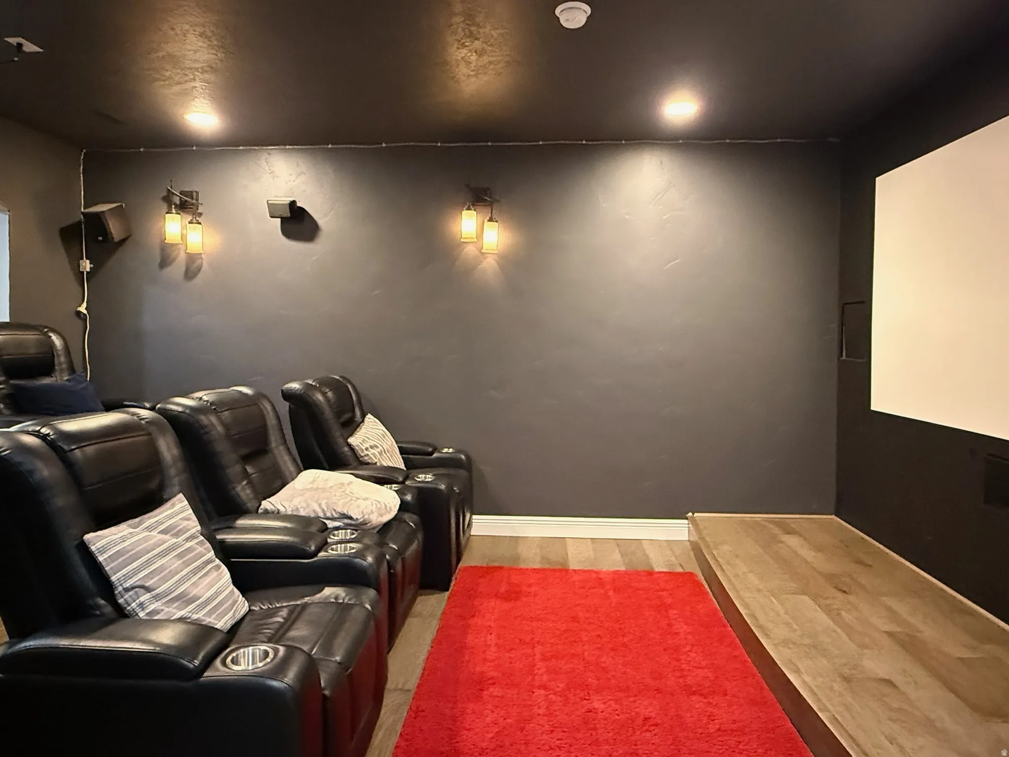 Dedicated media room featuring a large projection screen and tiered wood-finish flooring