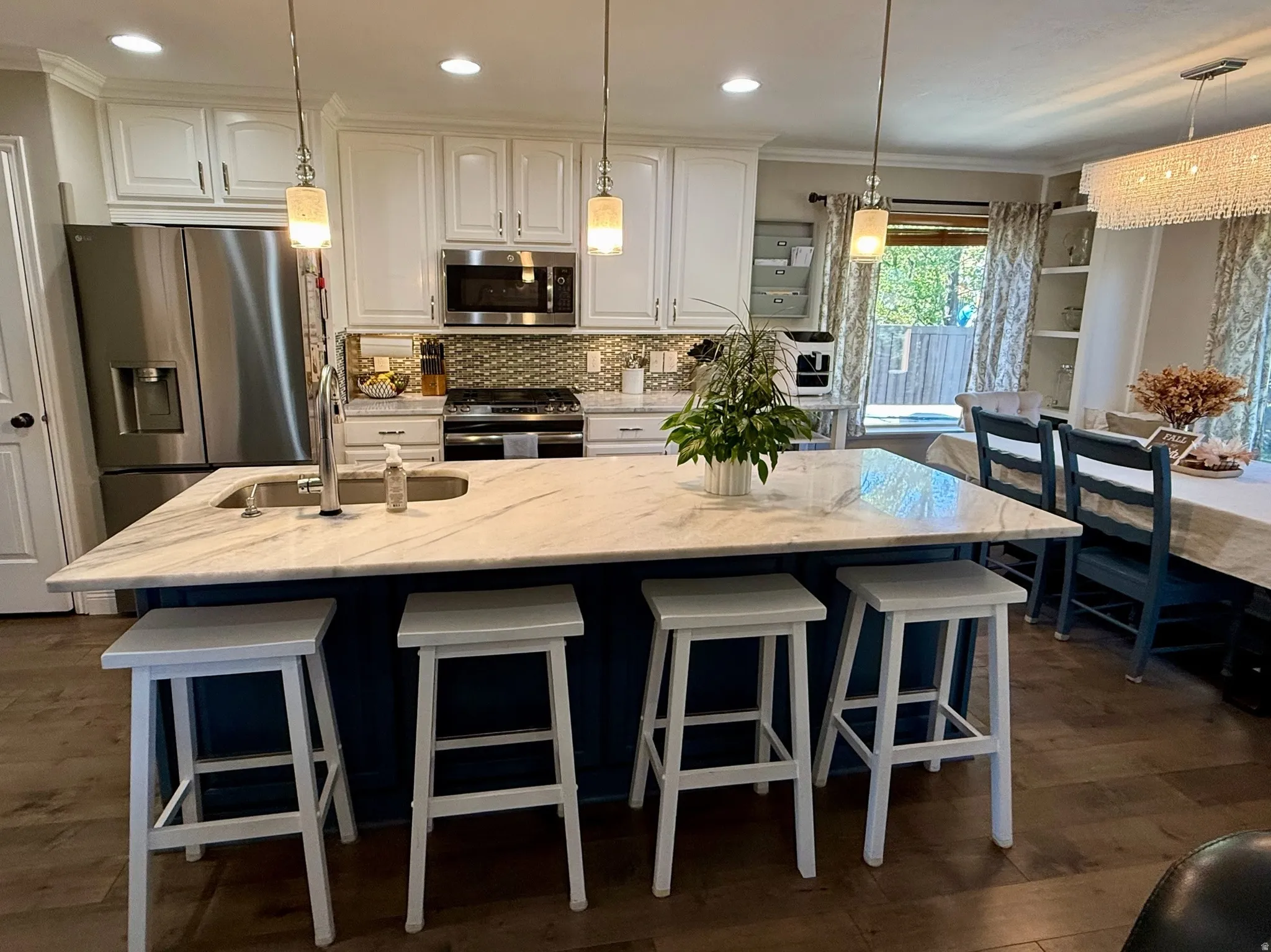 Kitchen island with white veined countertop, integrated sink, and pendant lighting