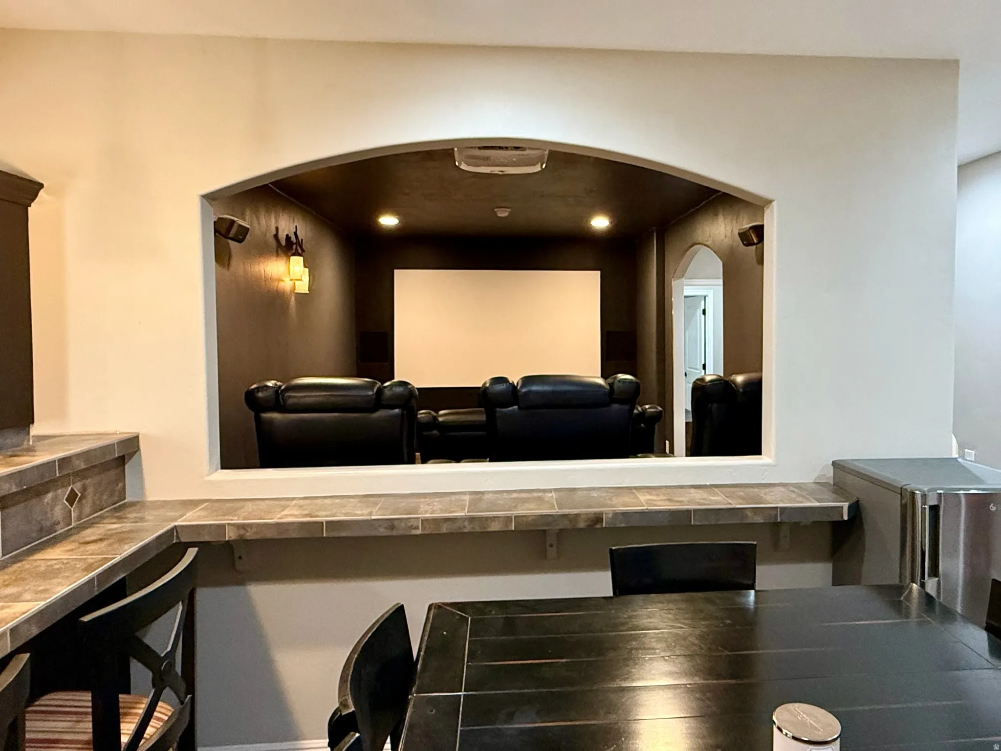 Dedicated media room featuring a large projection screen, recessed lighting, and wall-mounted sconces
