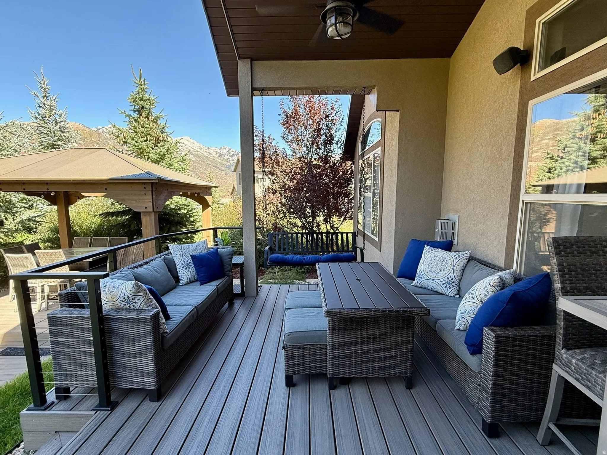 Expansive outdoor living area featuring a covered patio with a ceiling fan, composite decking, and cable railings