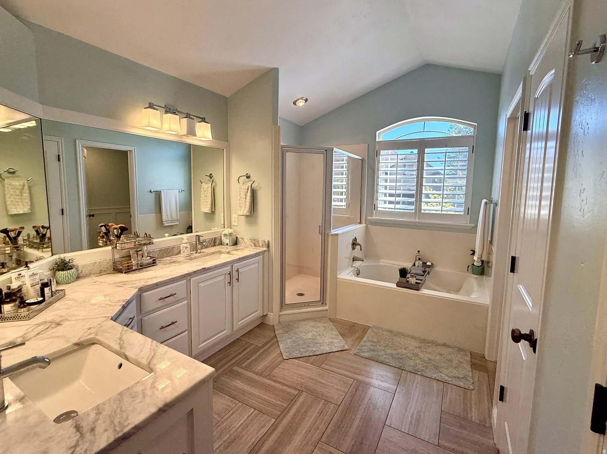 Master Bathroom featuring a double vanity with stone countertops, a soaking tub, and a glass-enclosed shower