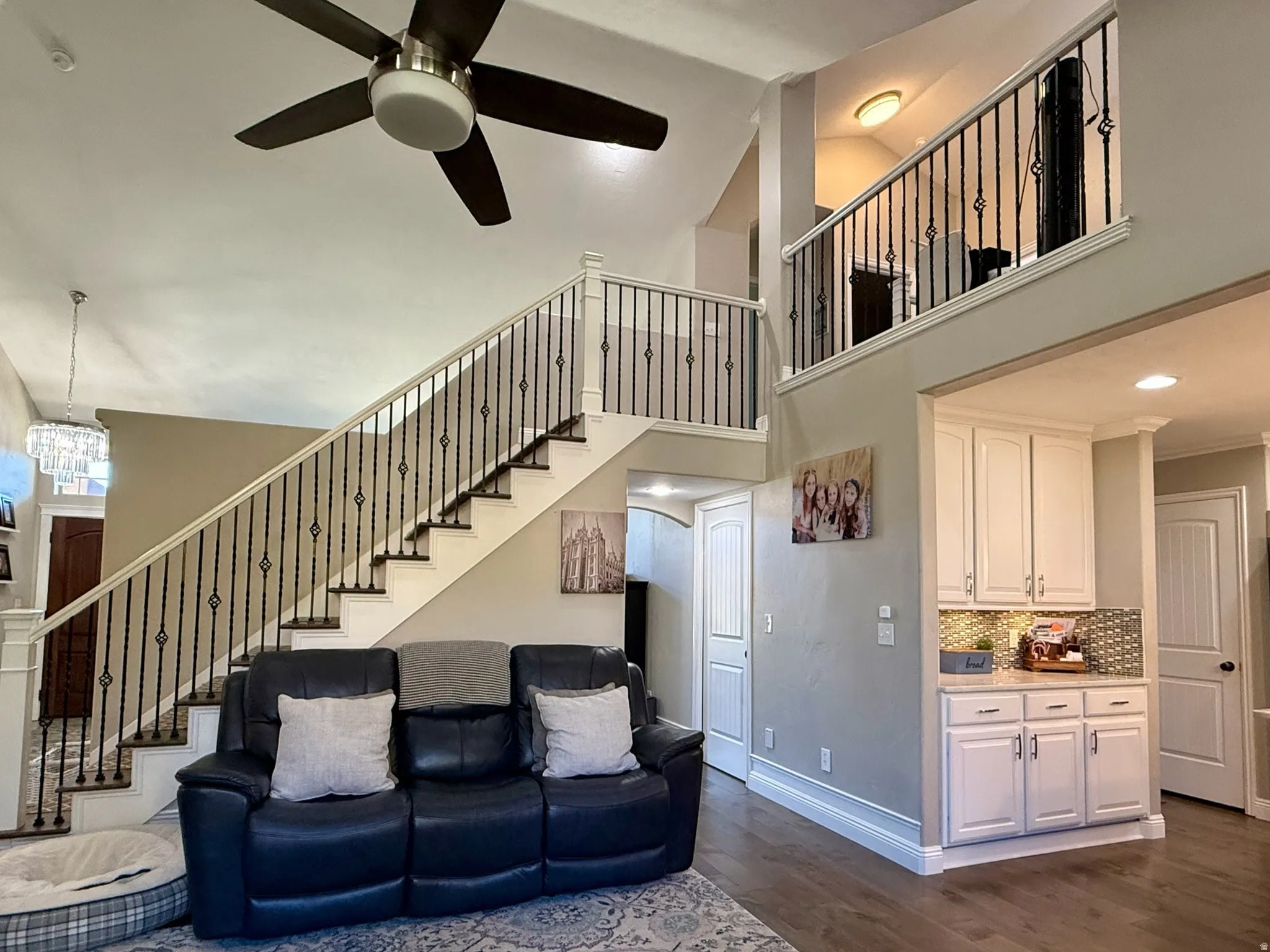 Two-story living space featuring a prominent staircase with decorative iron balusters and white risers