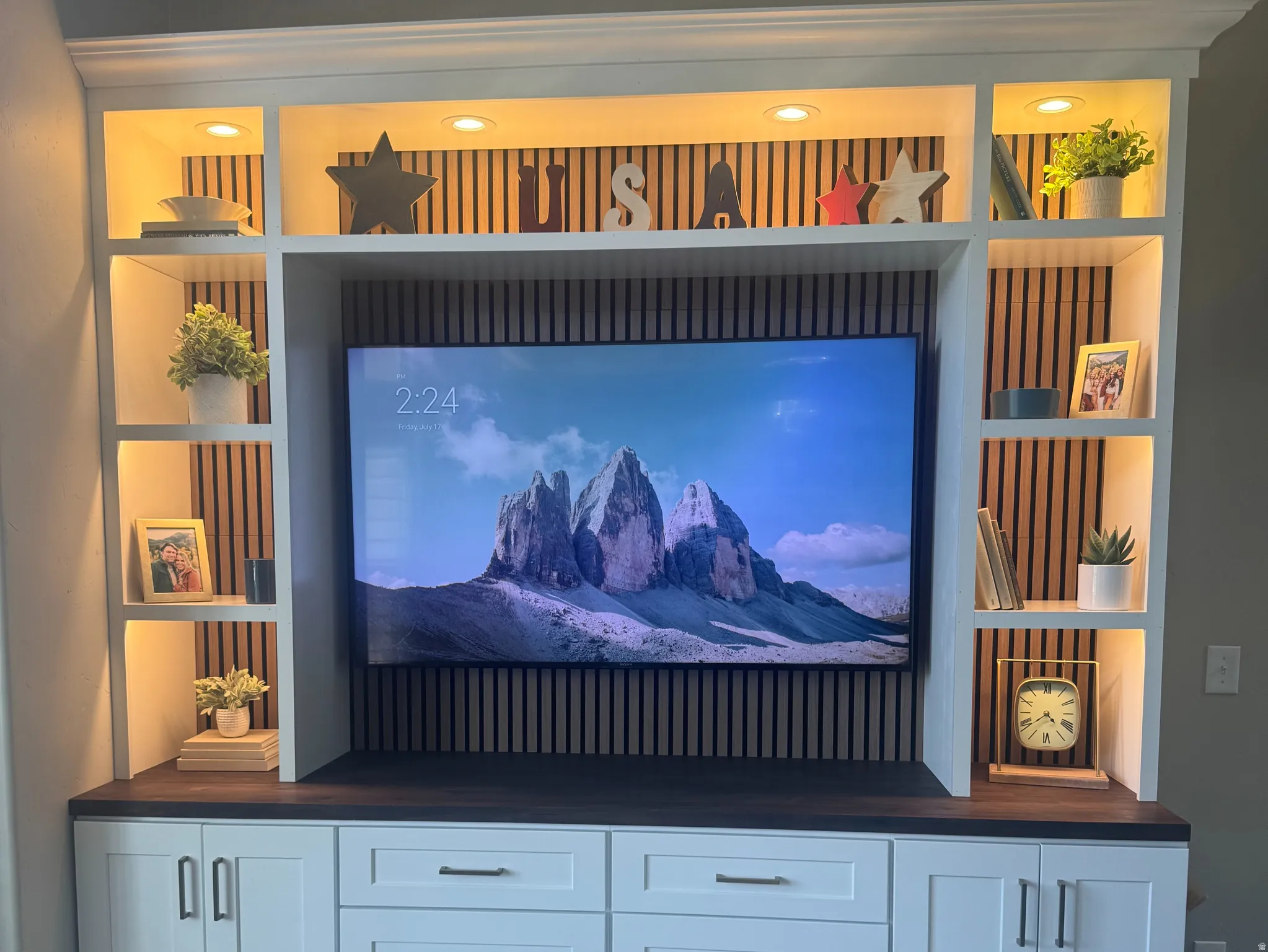 Brand new custom built-in media center featuring white cabinetry, dark wood-finish countertops, and recessed lighting in upper shelving