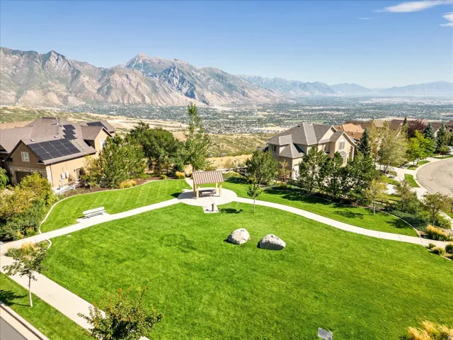 Across the street from the Neighborhood pocket park. Expansive green space featuring a paved walking path, a shaded pavilion, and mountain backdrop