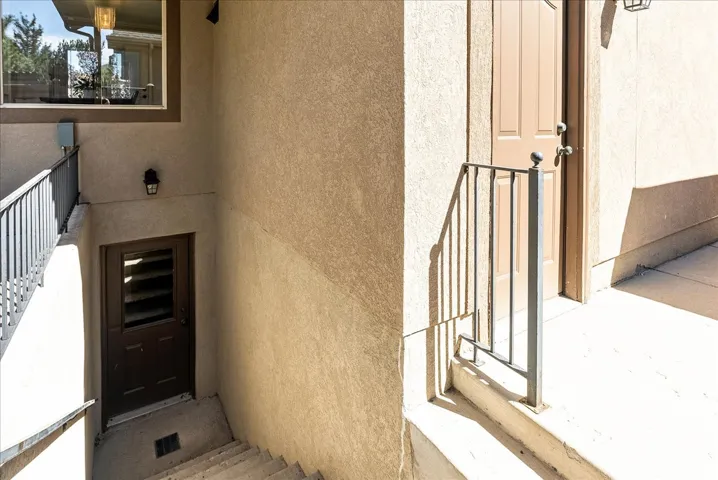 Walk out basement-Stucco exterior with a ground-level entrance, exterior lighting, and a metal handrail
