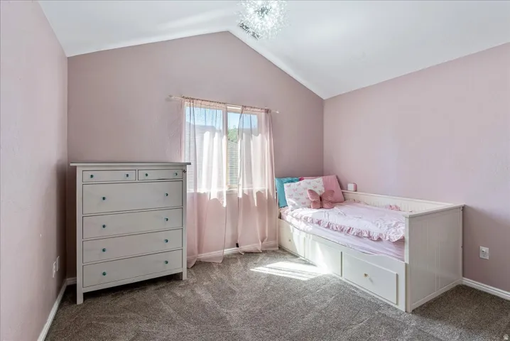 Vaulted ceiling, central window, wall-to-wall carpeting, and a decorative ceiling light fixture