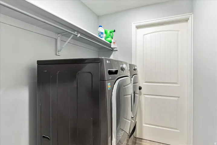 Second Laundry area featuring a built-in shelving unit, metal hanging rod, and a paneled door with an arched top