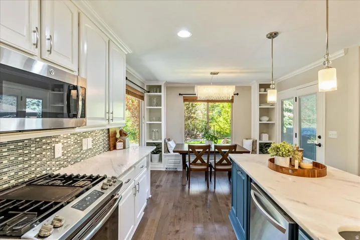 White cabinetry with stainless steel appliances, mosaic tile backsplash, and light-toned countertops