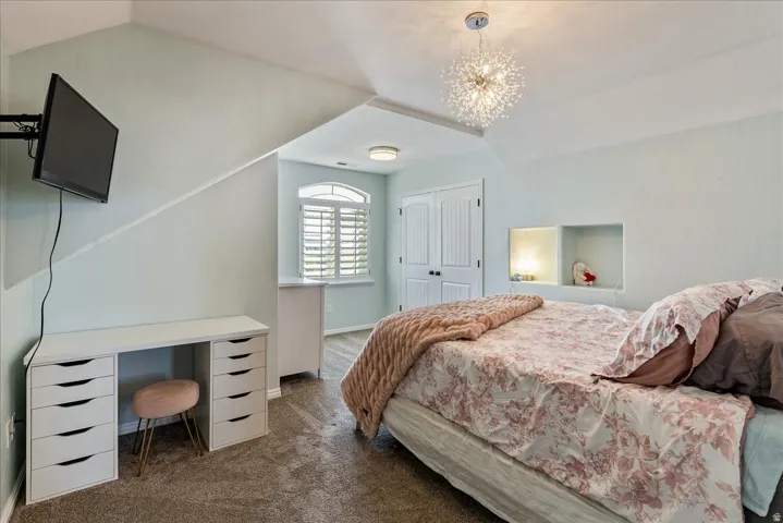 Built-in wall niche with integrated lighting, arched window with plantation shutters, double panel closet doors, and a decorative ceiling light fixture