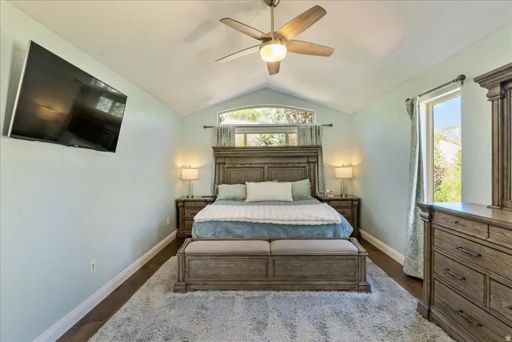 Primary Suite- Vaulted ceiling with a ceiling fan, wood-finish flooring, and a wall-mounted display