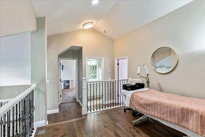 Loft-Vaulted ceilings, wood-finish flooring, white railing with wrought iron balusters, and recessed lighting