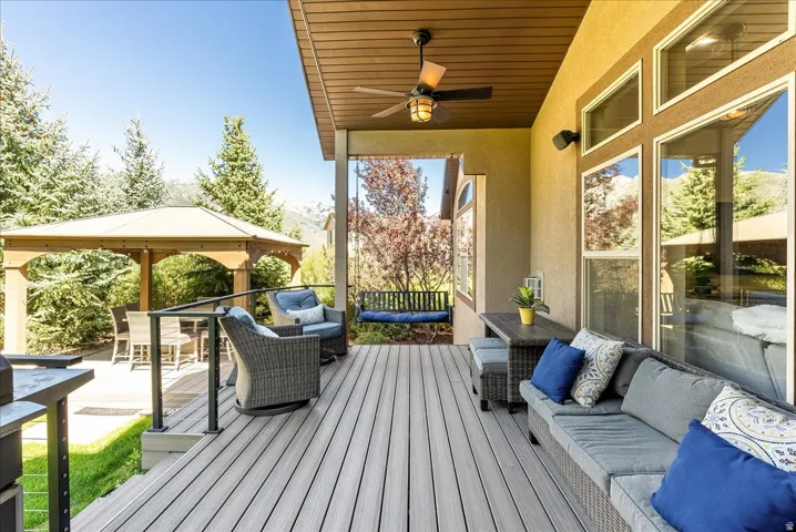 Covered outdoor deck with light gray composite flooring, black ceiling fan, recessed lighting, and a wooden gazebo