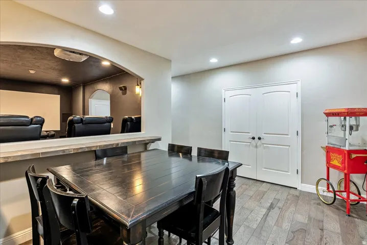Entertainment room featuring a projection screen, built-in shelving, recessed lighting, and wood-finish flooring
