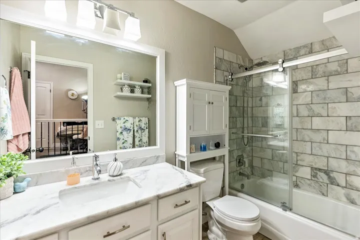 Vanity with a rectangular sink, stone countertop, and white cabinetry