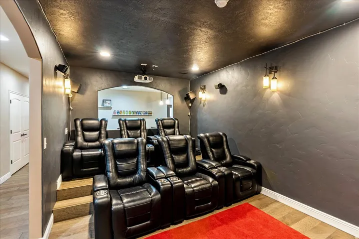 Dedicated media room featuring tiered seating, recessed ceiling lighting, and wall-mounted sconces
