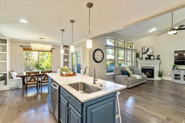 Central kitchen island with an undermount sink, built-in dishwasher, and pendant lighting