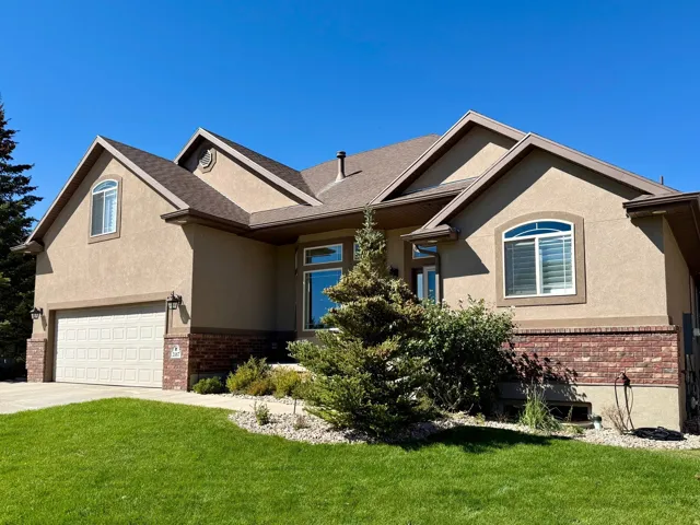 Stucco exterior with brick detailing, an attached garage, and a gabled roofline
