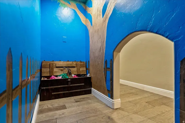 Kids under the stairs playroom with a tree mural and wood-finish flooring