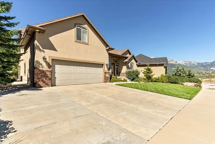 Stucco exterior with stone accents, a two-car garage, and a concrete driveway