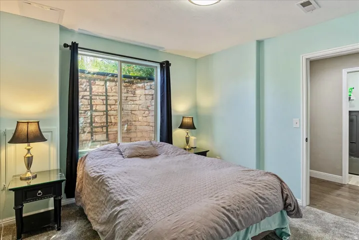 Window with stone retaining wall, recessed ceiling light, wall-mounted air vent, and carpeted flooring