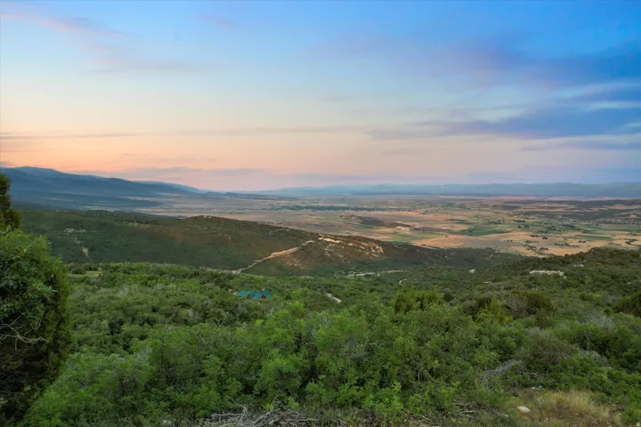 Expansive natural landscape featuring rolling hills and distant valleys under a clear sky