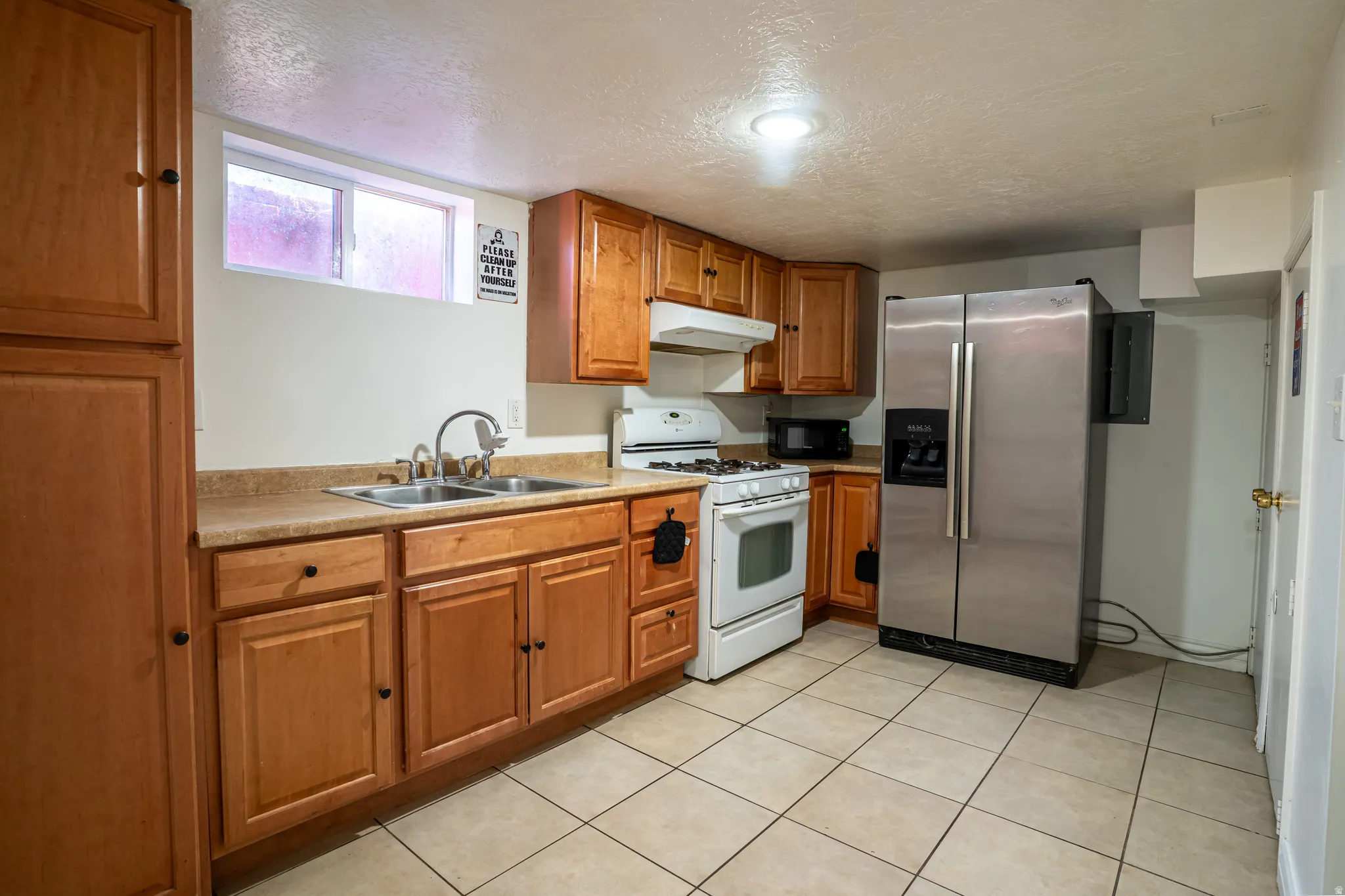 Kitchen featuring wood-finish cabinetry, tile flooring, and stainless steel refrigerator