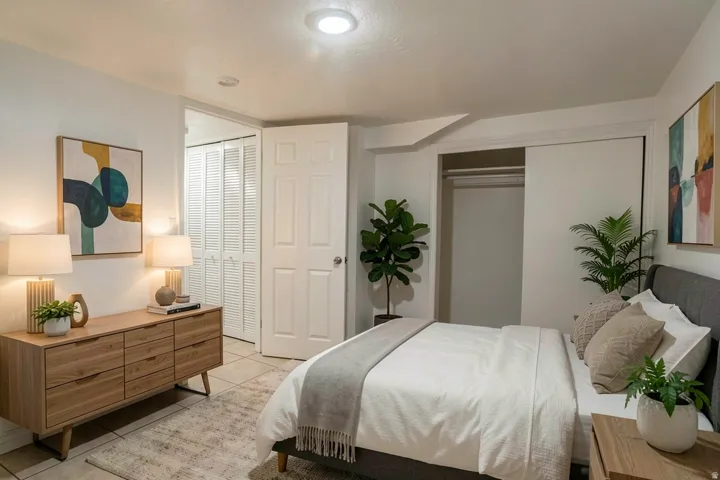 Recessed ceiling light, white paneled door, louvered bi-fold closet doors, tile flooring, and a sliding closet door