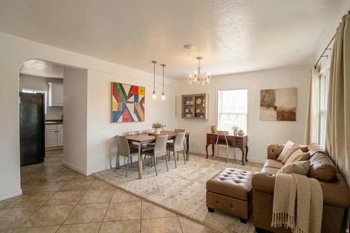 Open-concept living and dining area featuring tile flooring, a dining table with pendant lighting, and a chandelier