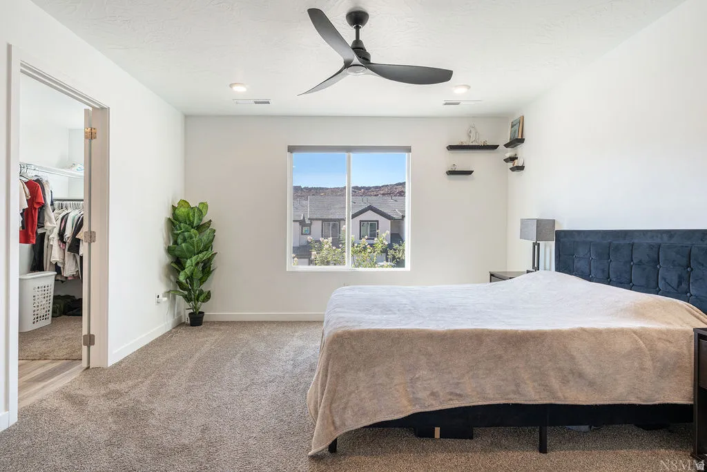 Carpeted bedroom featuring a large window, a ceiling fan with integrated lighting, and recessed lighting