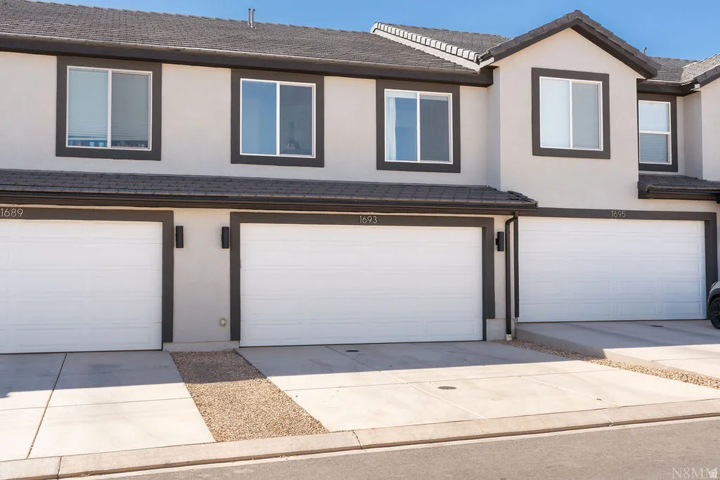 Townhome exterior featuring light-colored stucco siding with dark trim accents